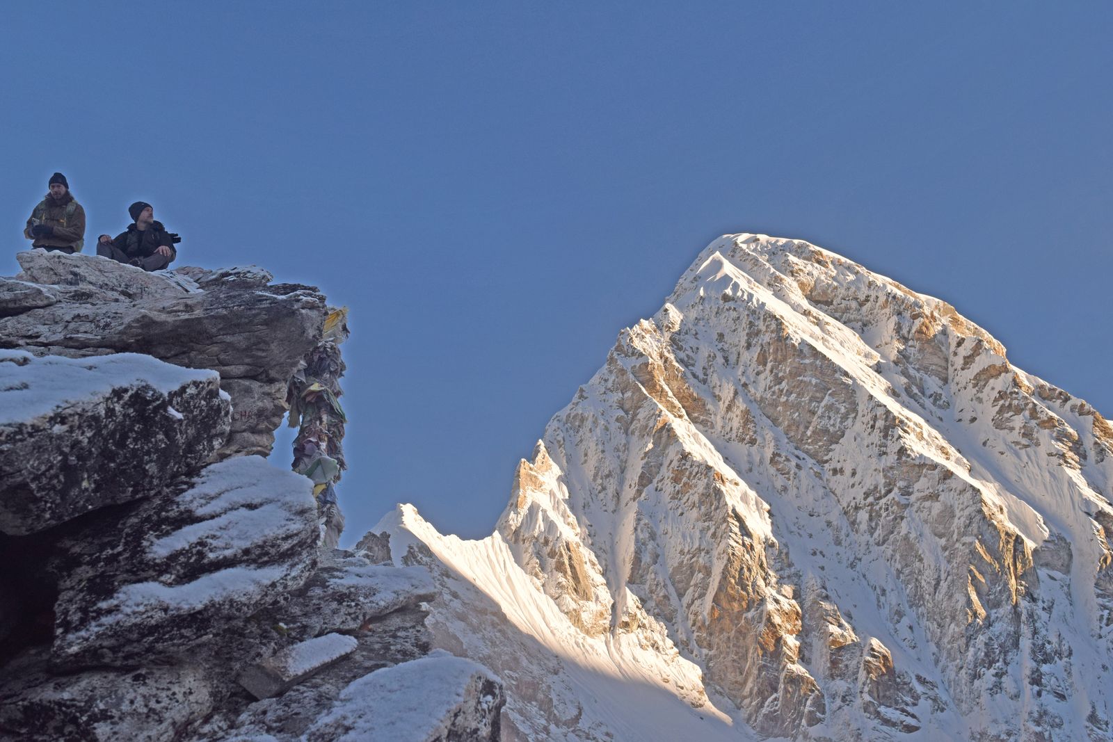 Lane Belone and Ashley Johnson on the summit rocks of Kala Patthar at sunrise, with Pumori beside them